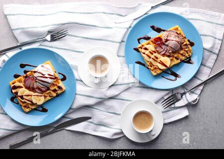 Tasty waffles with delicious fruits, ice-cream and syrup on blue plates Stock Photo