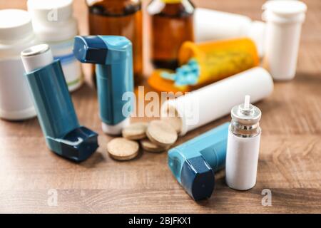 Asthma inhalers with medicines on wooden table Stock Photo