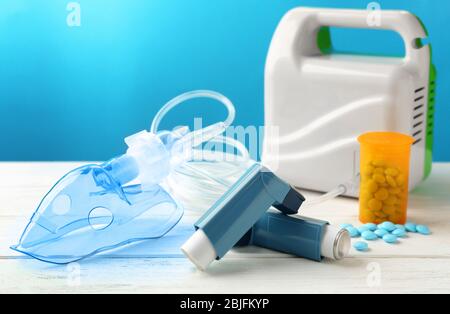 Asthma inhalers, nebuliser and pills on blue background Stock Photo