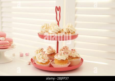 Dessert stand with tasty cupcakes on table Stock Photo