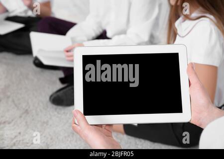 Tablet in female teacher's hands while conducting lesson at school Stock Photo