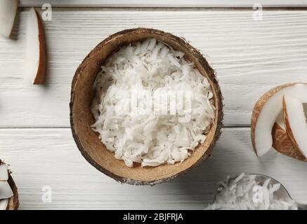 Grated coconut in shell on wooden background Stock Photo