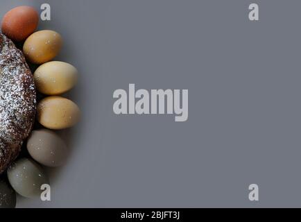 Easter colored eggs are laid out in a semicircle adjacent to the cake on the edge of the frame. Space for text. Gray background Stock Photo