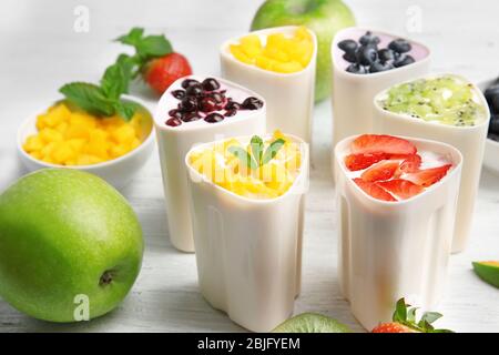 Bowls from automatic yogurt maker with fruits on wooden background Stock Photo