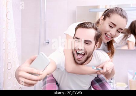 Young happy couple taking selfie while brushing teeth in bathroom Stock Photo