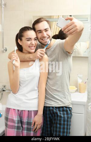 Young happy couple taking selfie while brushing teeth in bathroom Stock Photo