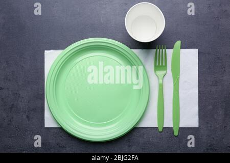 Green plastic disposable tableware on gray background Stock Photo