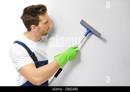 Young window cleaner with poster on white background Stock Photo