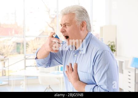 Elderly man using inhaler in clinic Stock Photo