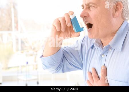 Elderly man using inhaler in clinic Stock Photo
