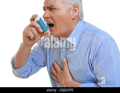 Elderly man using inhaler on white background Stock Photo