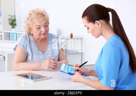 Female orthopedist examining senior woman in clinic Stock Photo