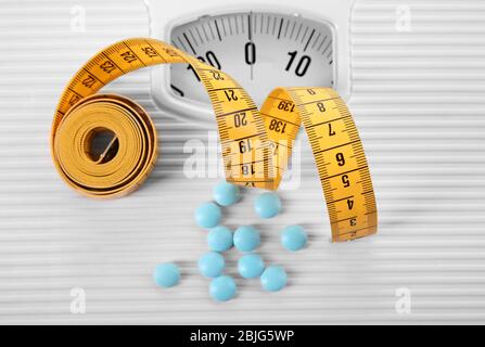 Diet concept. Measuring tape with pills and scales on background Stock Photo