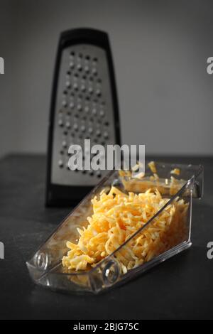 https://l450v.alamy.com/450v/2bjg75c/plastic-container-with-cheese-and-grater-on-table-2bjg75c.jpg