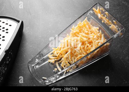 Grated cheese in plastic container on table Stock Photo