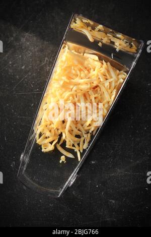 Plastic container with grated cheese on table Stock Photo