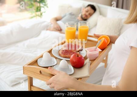 Woman bringing tray with breakfast to bed Stock Photo