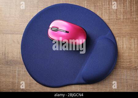 Modern wireless mouse and pad on wooden background Stock Photo
