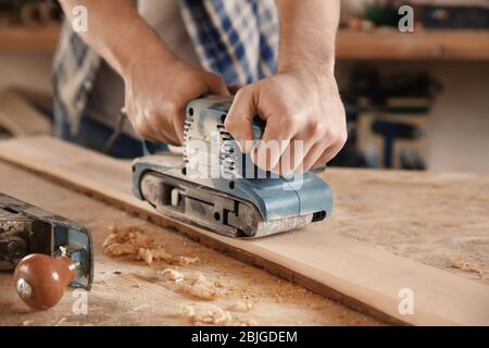 Carpenter working with electric sander in shop Stock Photo
