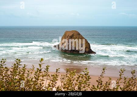 A peaceful Oregon beach coastline with Jockey Cap Rock in the middle, crashing ocean waves. Nature Landscape Background. Island near Tolovana Park, Ca Stock Photo