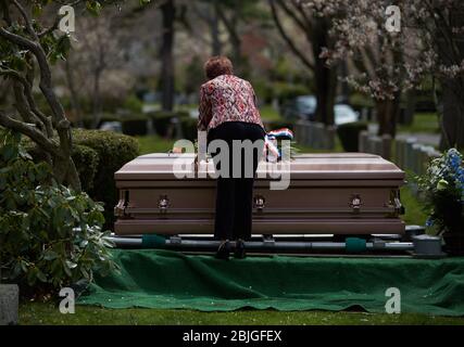 Everett, Massachusetts, USA. 28th Apr, 2020. The COVID-19, Corona Virus in Massachusetts is the third worst hit state in America. The Woodlawn Cemetery in Everett, MA is doing 3x the normal amount of funerals. A woman grieves on a casket. Credit: Allison Dinner/ZUMA Wire/Alamy Live News Stock Photo