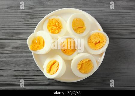 Ceramic tray with sliced hard boiled eggs on wooden table. Nutrition concept Stock Photo