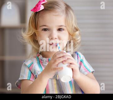 Cute little girl drinking yogurt at home Stock Photo