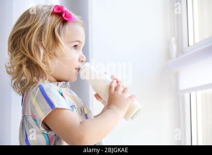 Cute little girl drinking yogurt at home Stock Photo