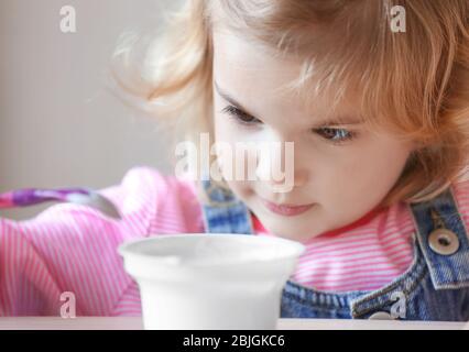 Cute little girl eating yogurt at home, closeup Stock Photo