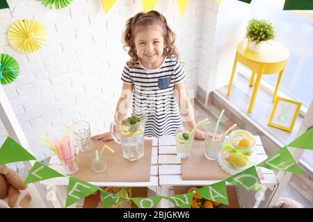 Cute little girl selling lemonade at counter Stock Photo