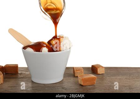 Pouring caramel sauce onto ice cream in bowl against white background Stock Photo