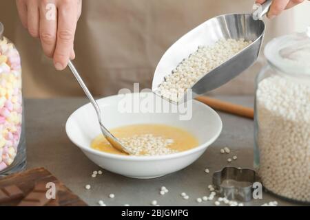 Woman adding crispy rice balls into bowl on table Stock Photo