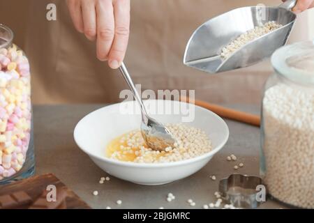 Woman adding crispy rice balls into bowl on table Stock Photo