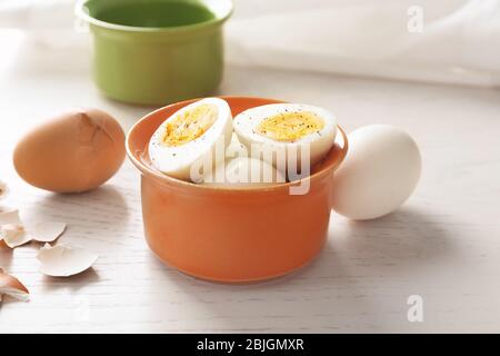 Bowl with sliced hard boiled eggs on light background. Nutrition concept Stock Photo