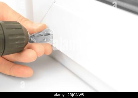 Man drilling a hole in window frame at home Stock Photo