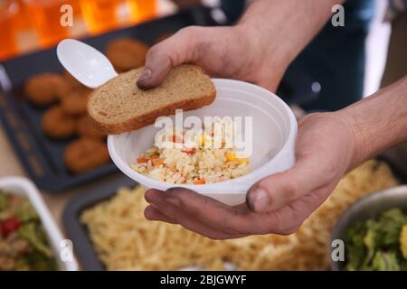 Hands of poor man holding bowl with rice and bread. Poverty concept Stock Photo