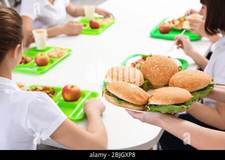 https://l450v.alamy.com/450v/2bjgxp8/woman-serving-plate-with-delicious-sandwiches-to-children-at-school-canteen-2bjgxp8.jpg