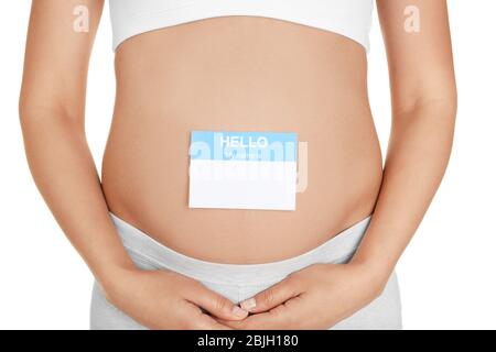 Closeup of pregnant woman with paper sticker on tummy, against white background. Concept of choosing baby name Stock Photo