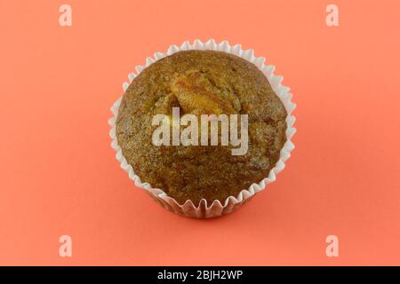 Baked carrot muffin in white paper muffin cup in orange background Stock Photo