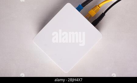 Wi-Fi router modem with connected cables on a white background close-up top view. Stock Photo