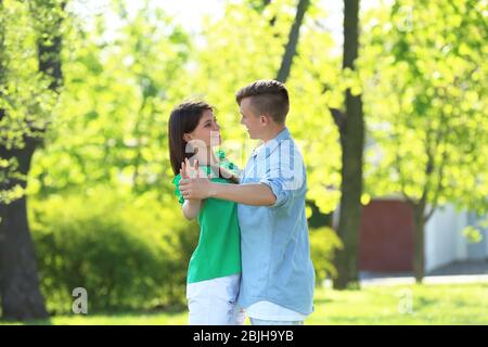 Beautiful young couple dancing in park on sunny day Stock Photo