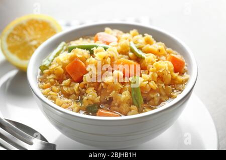Bowl with tasty lentil porridge and vegetables on table, closeup Stock Photo