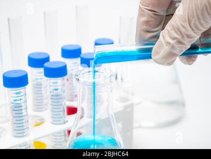 A researcher's hand holding a test tube containing blue liquid. Stock Photo