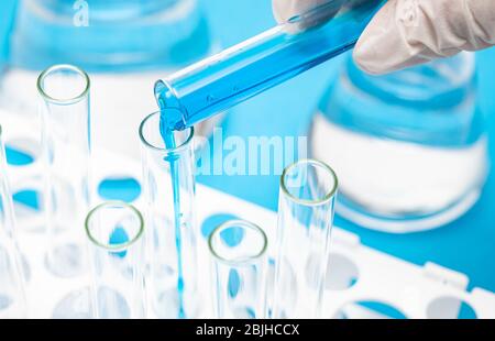 A researcher's hand holding a test tube containing blue liquid. Stock Photo