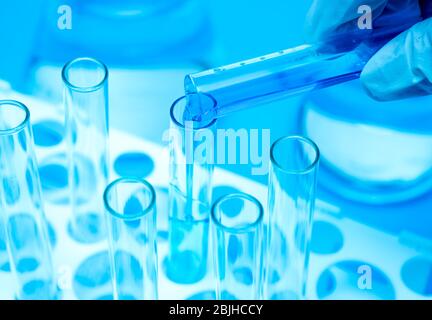 A researcher's hand holding a test tube containing blue liquid. Stock Photo