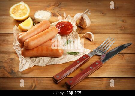 Yummy grilled sausages with sauce on brown wooden table Stock Photo