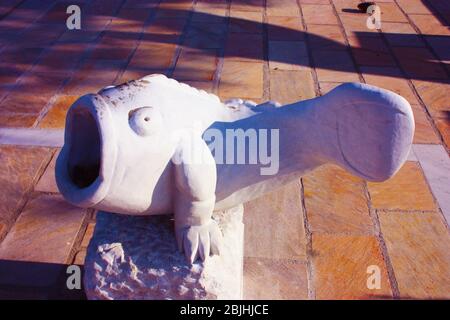 strange statue in white marble depicting a fat fish with a big mouth wide open in a tiled garden in tuscany Stock Photo