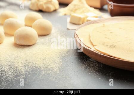 Wooden plate with rolled dough and balls for tortillas on kitchen table Stock Photo