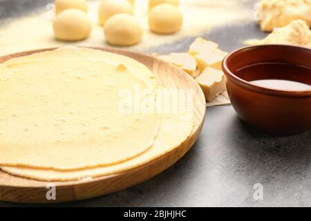 Wooden plate with rolled dough for tortillas on kitchen table Stock Photo