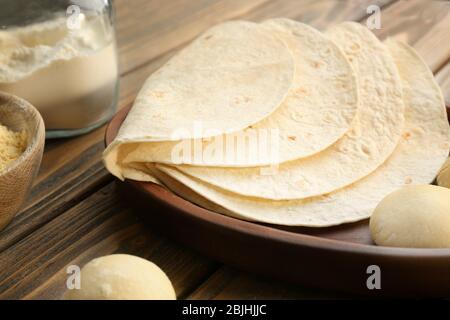 Delicious tortillas and dough balls on kitchen table Stock Photo
